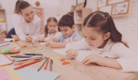 Des enfants dessinent à une table avec une animatrice