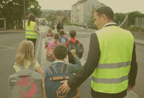 Un agent en gilet jaune fait traverser des écoliers